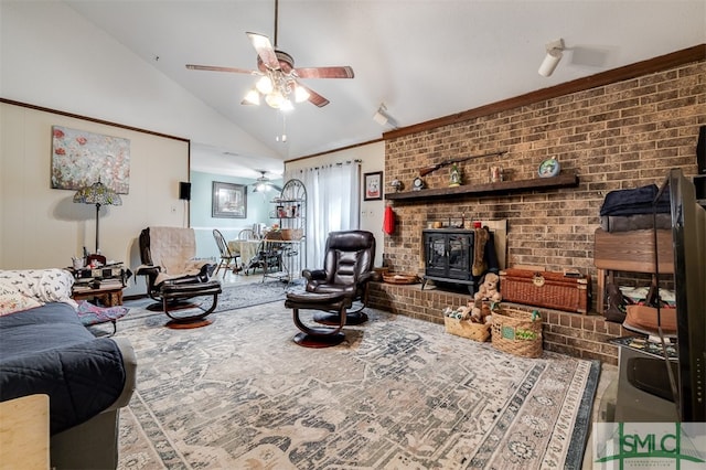 living room with a wood stove, vaulted ceiling, ceiling fan, ornamental molding, and brick wall