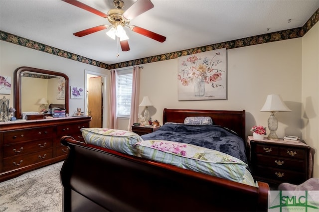 carpeted bedroom with ceiling fan and a textured ceiling