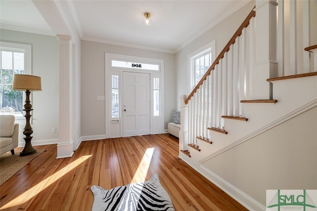 entryway with crown molding, a healthy amount of sunlight, and light wood-type flooring