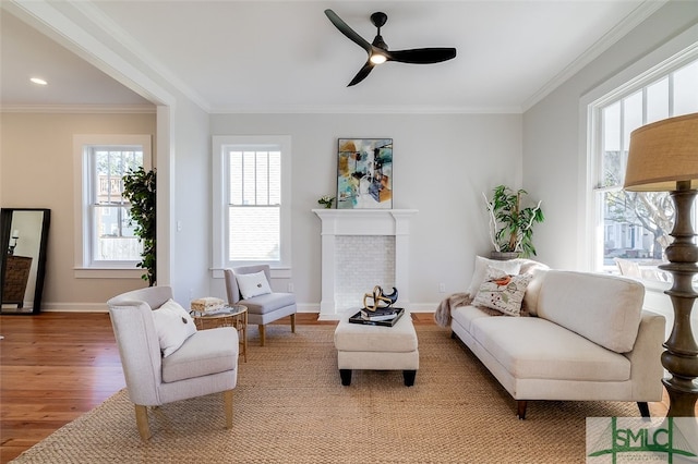 living room featuring light wood-type flooring, ceiling fan, and crown molding