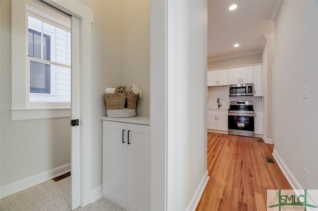 hall with light wood-type flooring and crown molding