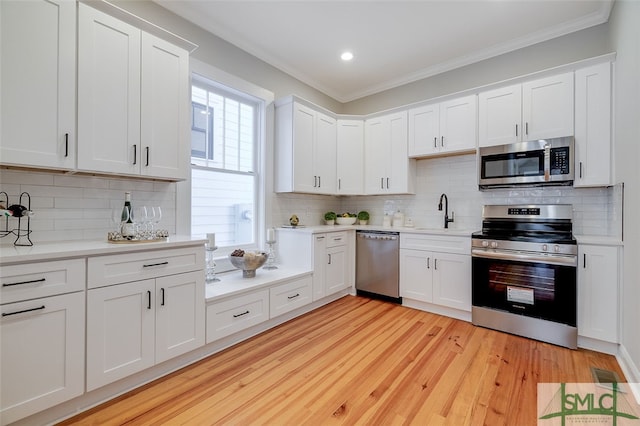 kitchen with white cabinets, stainless steel appliances, tasteful backsplash, and crown molding