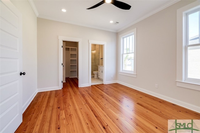 unfurnished bedroom featuring ensuite bathroom, ceiling fan, light wood-type flooring, and a spacious closet