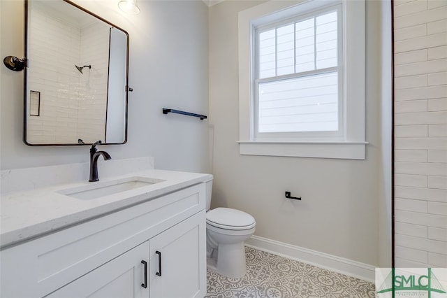 bathroom featuring tile patterned flooring, a tile shower, vanity, and toilet