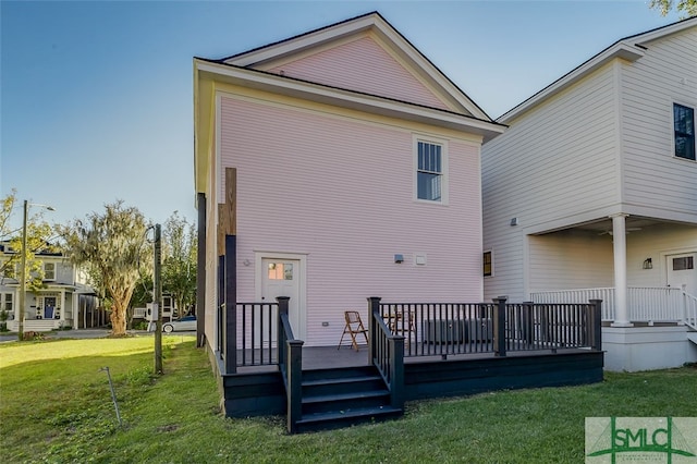 back of house featuring a lawn and a deck