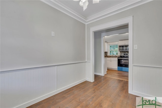 unfurnished room featuring hardwood / wood-style flooring, ornamental molding, and sink