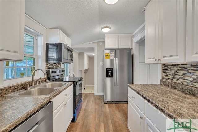 kitchen featuring white cabinets, sink, light hardwood / wood-style flooring, decorative backsplash, and stainless steel appliances