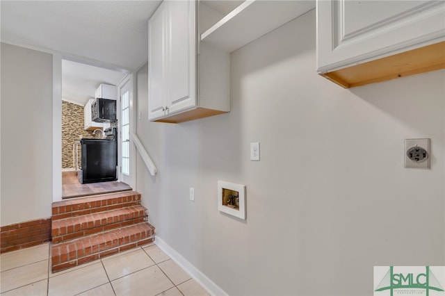 laundry area with hookup for a washing machine, light tile patterned flooring, and cabinets