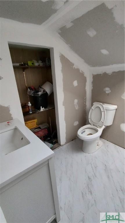 bathroom with marble finish floor, toilet, and a sink