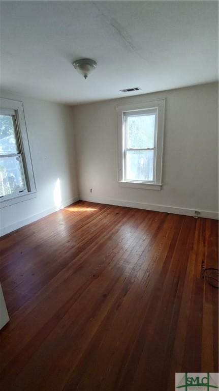 empty room with visible vents, baseboards, and dark wood-style floors