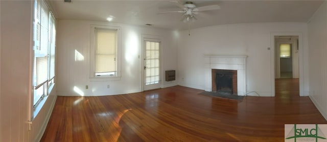 unfurnished living room featuring visible vents, ceiling fan, a fireplace, heating unit, and wood-type flooring