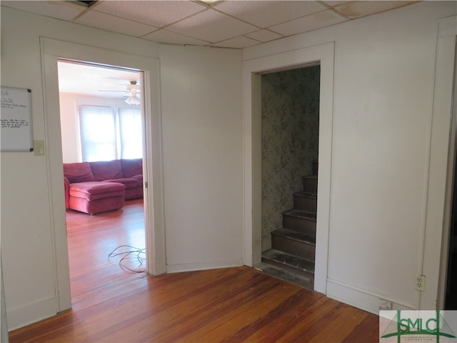 hallway featuring wood-type flooring and a drop ceiling