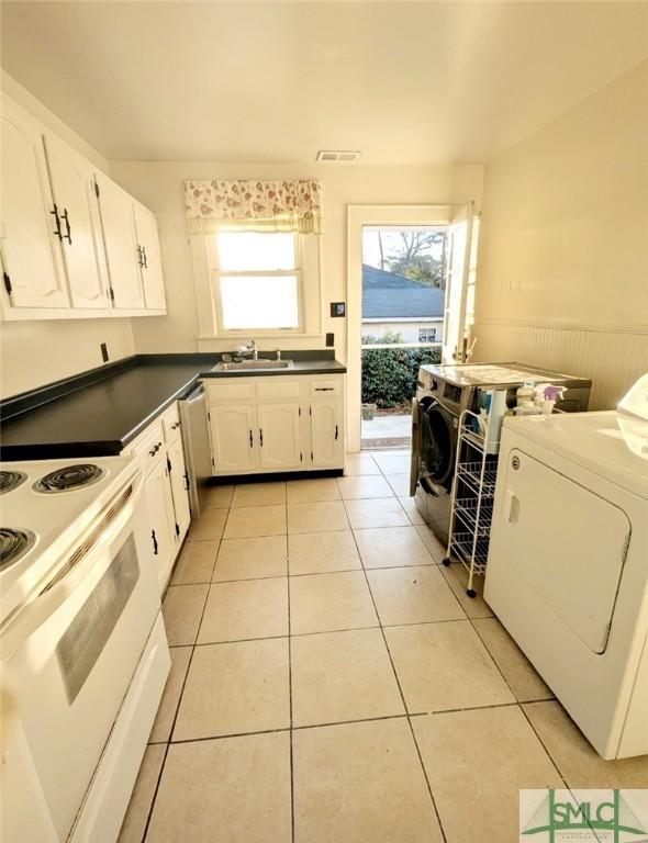 kitchen featuring white range with electric cooktop, dark countertops, dishwasher, and washer and clothes dryer