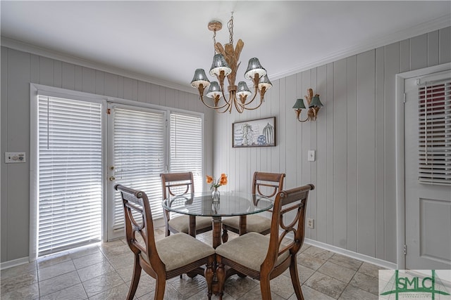 dining room featuring wood walls, ornamental molding, and an inviting chandelier