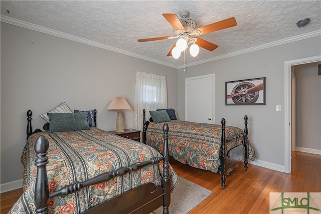 bedroom with a textured ceiling, ceiling fan, wood-type flooring, and ornamental molding