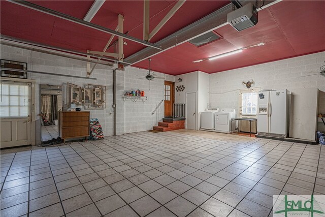 garage with washer and dryer, white refrigerator with ice dispenser, and a garage door opener