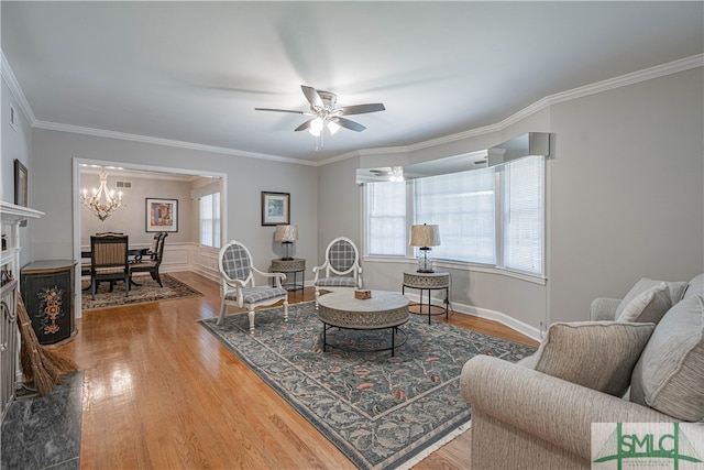 living room with a fireplace, ceiling fan with notable chandelier, hardwood / wood-style flooring, and ornamental molding