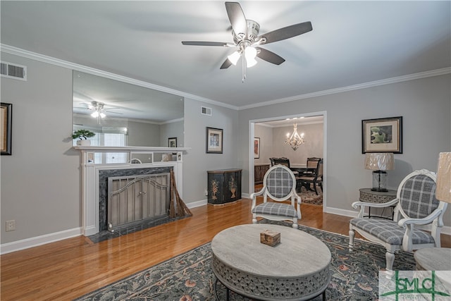 living room with hardwood / wood-style flooring, a fireplace, ceiling fan, and crown molding