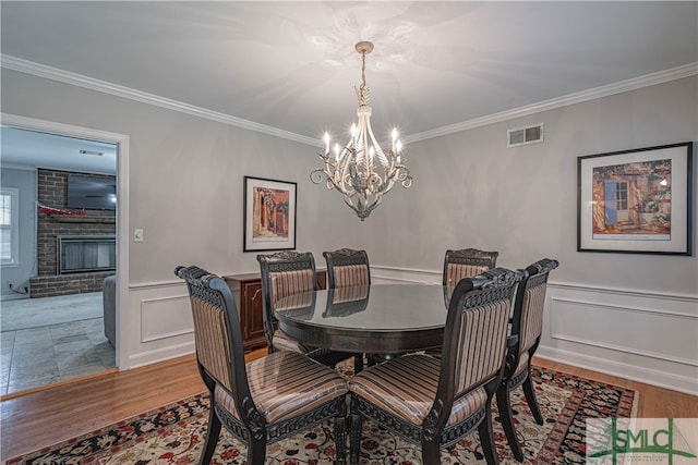 dining space featuring hardwood / wood-style floors, a brick fireplace, and ornamental molding