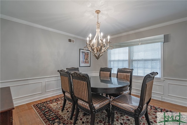 dining space featuring an inviting chandelier, a water view, ornamental molding, and hardwood / wood-style flooring