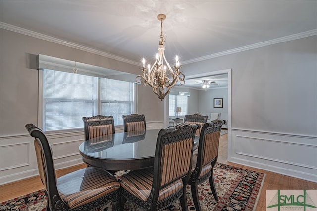 dining room with ceiling fan with notable chandelier, ornamental molding, and light hardwood / wood-style flooring