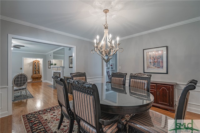 dining space featuring ornamental molding, ceiling fan with notable chandelier, and hardwood / wood-style flooring