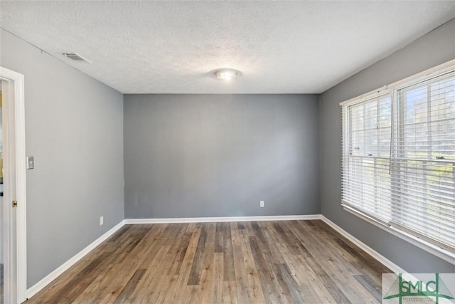 unfurnished room with a textured ceiling and hardwood / wood-style flooring