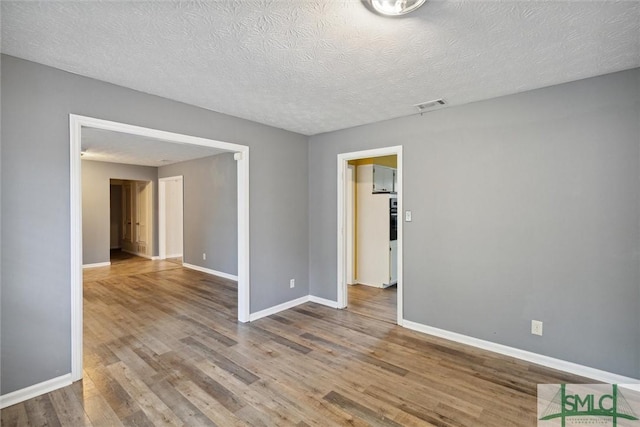 empty room with a textured ceiling and hardwood / wood-style flooring