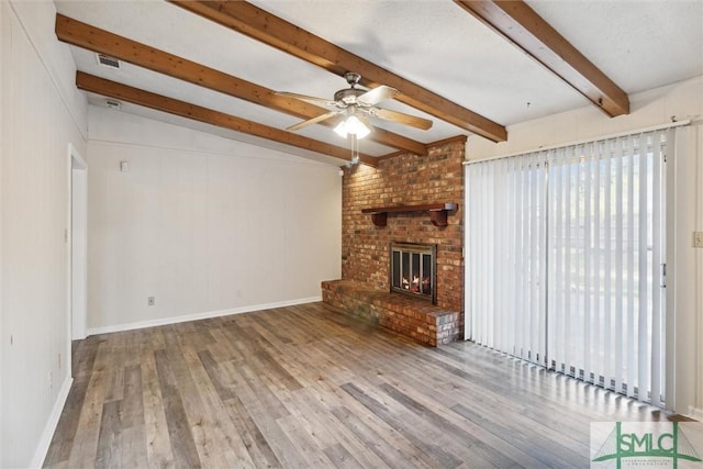 unfurnished living room featuring vaulted ceiling with beams, ceiling fan, a fireplace, and light hardwood / wood-style flooring