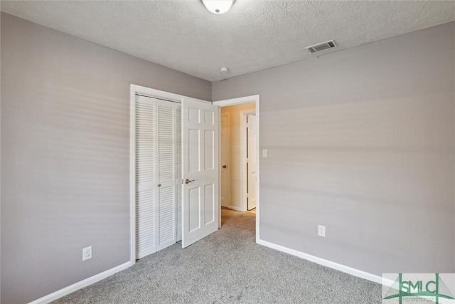 unfurnished bedroom featuring a textured ceiling, light colored carpet, and a closet