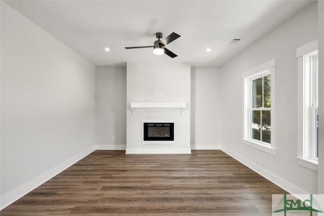 unfurnished living room with ceiling fan and dark wood-type flooring