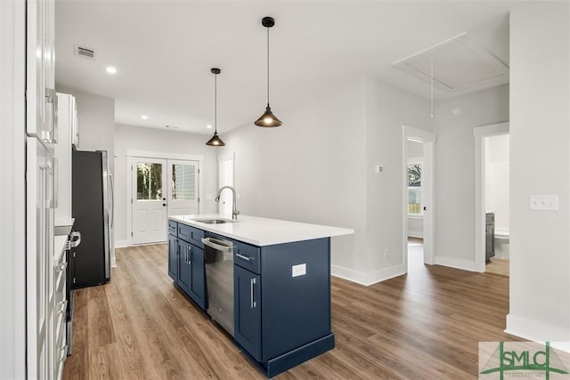 kitchen with blue cabinets, sink, an island with sink, appliances with stainless steel finishes, and white cabinetry