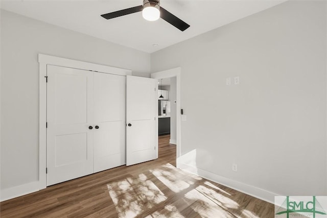 unfurnished bedroom with ceiling fan, stainless steel fridge, wood-type flooring, and a closet