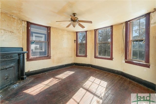 interior space with ceiling fan, a fireplace, and dark wood-type flooring