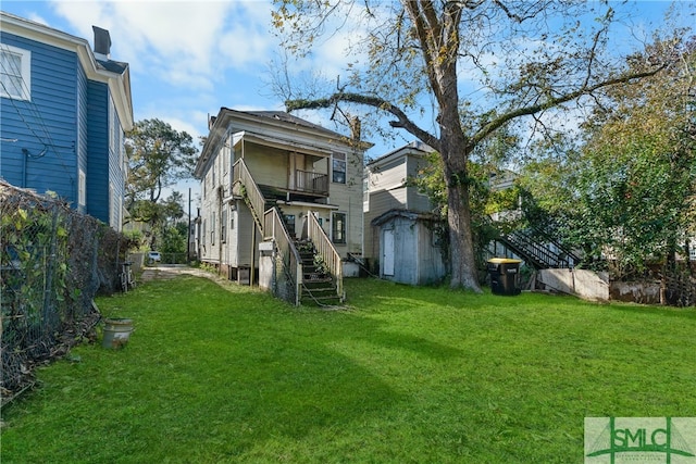 rear view of house with a yard, a balcony, and a storage shed