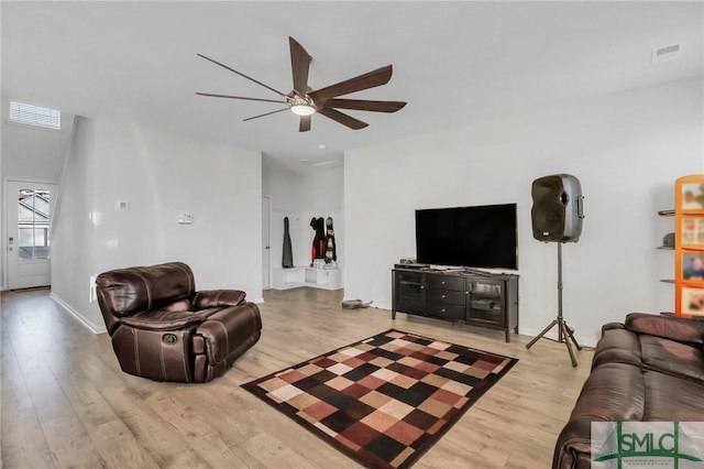 living room with visible vents, baseboards, light wood-style floors, and a ceiling fan