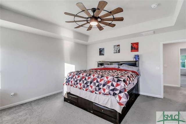 bedroom featuring a tray ceiling, baseboards, and carpet