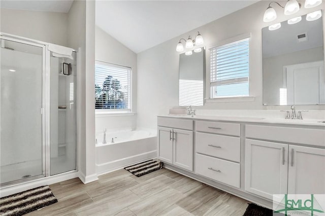 full bath with visible vents, lofted ceiling, double vanity, a stall shower, and a garden tub