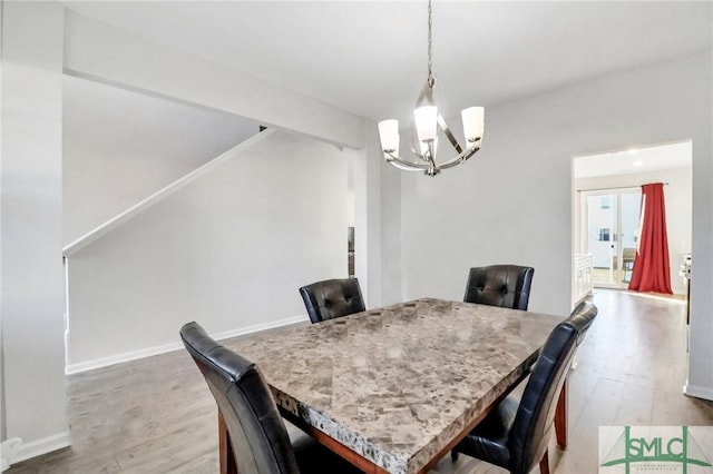 dining space featuring a notable chandelier, baseboards, and wood finished floors