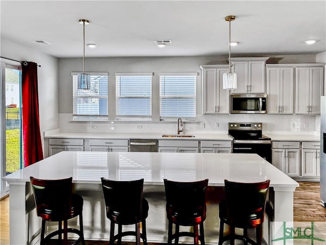 kitchen with light wood finished floors, visible vents, appliances with stainless steel finishes, and a sink