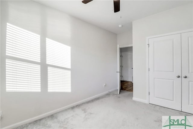 unfurnished bedroom featuring a closet, light carpet, baseboards, and a ceiling fan