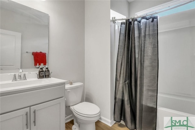 bathroom with vanity, toilet, wood finished floors, and baseboards