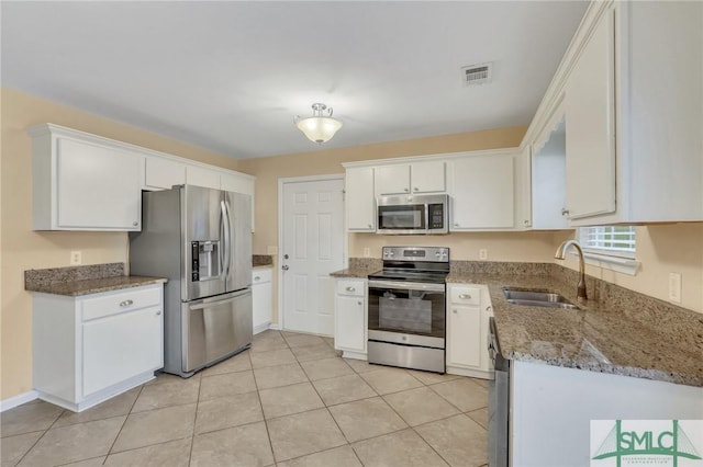 kitchen featuring stainless steel appliances, sink, stone counters, white cabinetry, and light tile patterned flooring