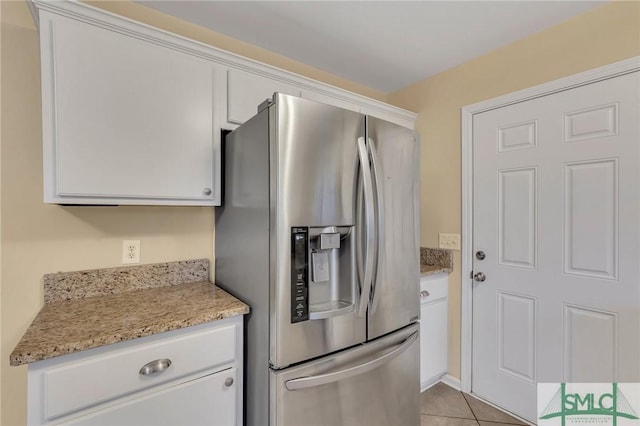 kitchen with white cabinets, light stone countertops, light tile patterned floors, and stainless steel refrigerator with ice dispenser