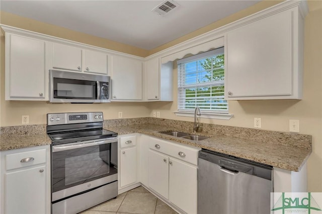 kitchen featuring white cabinetry, sink, light stone counters, light tile patterned flooring, and appliances with stainless steel finishes