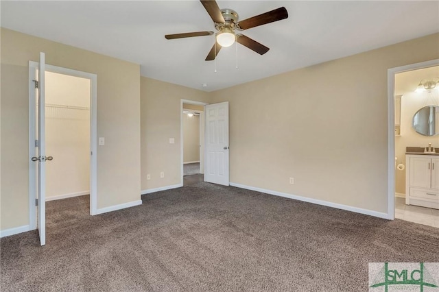 unfurnished bedroom with a spacious closet, ceiling fan, ensuite bathroom, carpet floors, and a closet