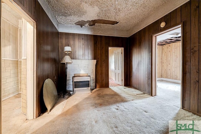 unfurnished living room featuring a fireplace, a textured ceiling, wooden walls, and light carpet