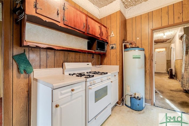 kitchen featuring water heater, white cabinets, white range with gas stovetop, and wood walls