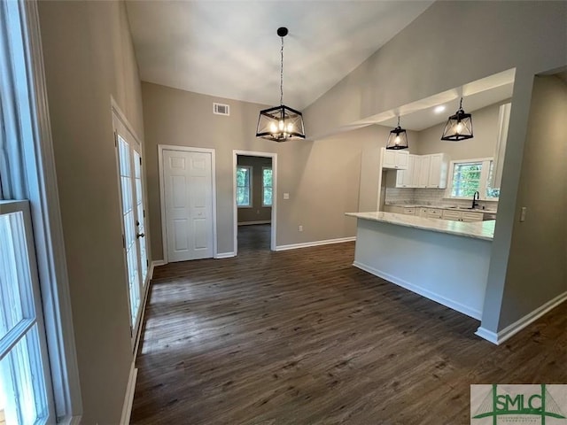 kitchen featuring dark hardwood / wood-style flooring, tasteful backsplash, a chandelier, white cabinetry, and hanging light fixtures