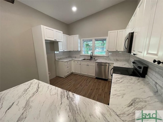 kitchen with appliances with stainless steel finishes, dark hardwood / wood-style flooring, tasteful backsplash, sink, and white cabinets